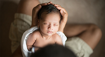 newborn baby cradled in father's hands