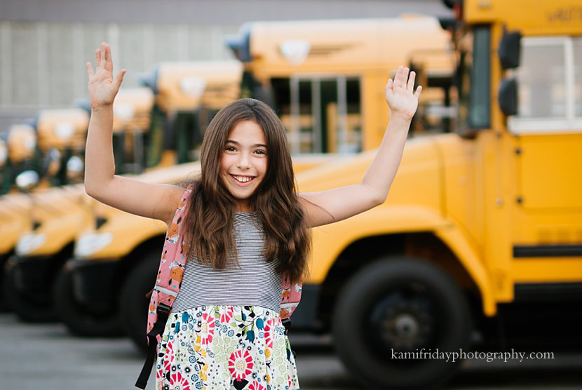 Girl poses for portrait in front of a Nashua NH school bus