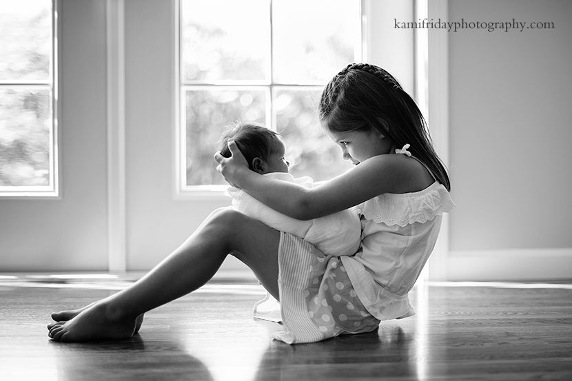 Hollis NH family and newborn photographer photographs young girl with her new baby sister.