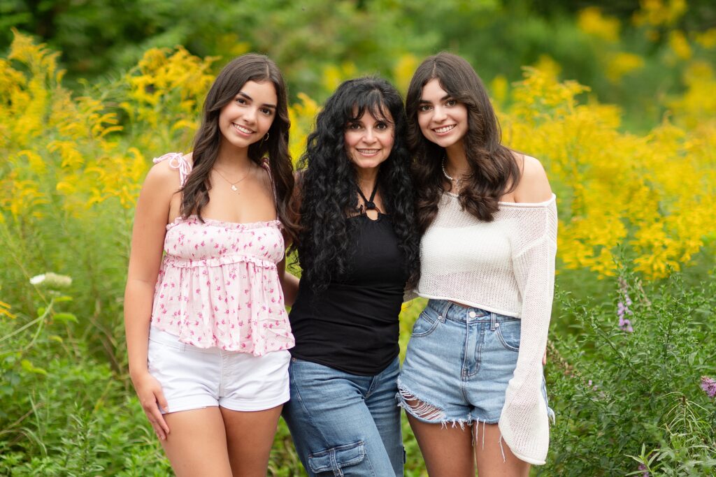 A NH mother poses with her 2 daughters in a field of yellow flowers.