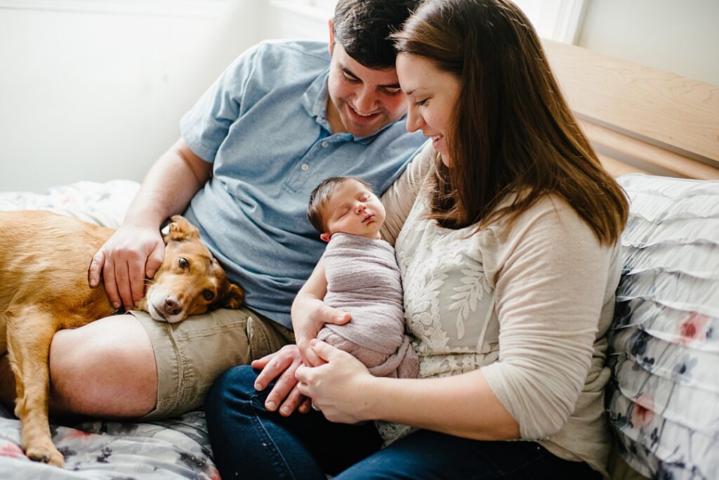 Parents sitting together holding their newborn baby during a relaxed lifestyle newborn photography session in Nashua NH