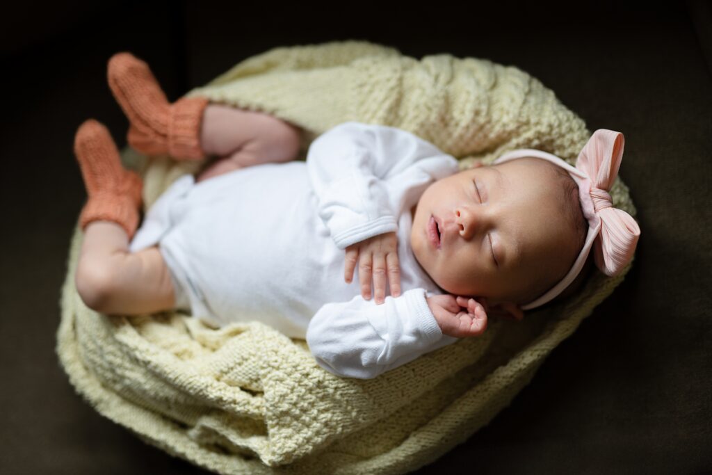 Newborn baby wrapped in blanket on parents’ couch during a Nashua NH newborn photo session