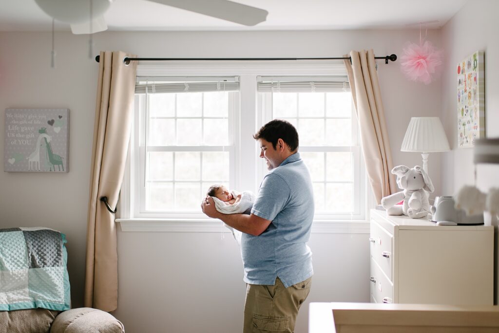 Father holding newborn baby in soft natural light during a Nashua NH newborn photography session
